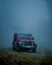 Red SUV driving on a foggy dirt road, capturing the spirit of off-road adventure and exploration.